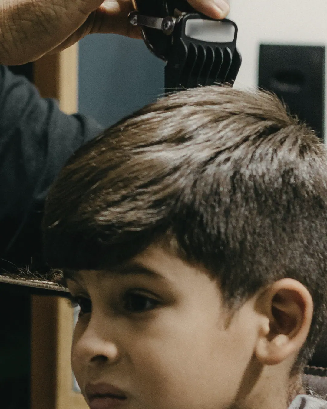 Menino cortando o cabelo na máquina com pente de altura